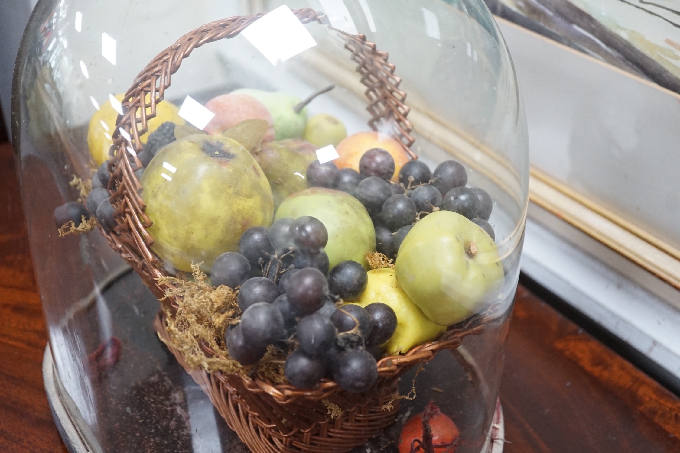 A Victorian wax fruit arrangement in a basket under glass dome, 34cms high